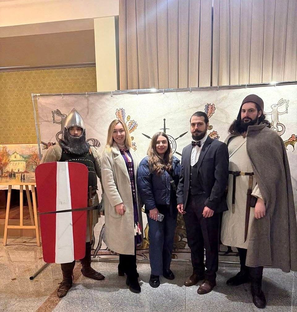 Atira Ruthenia members in medieval armour and clothing with guests in front of the club banner at the 10th anniversary conference, Kyiv, December 2025