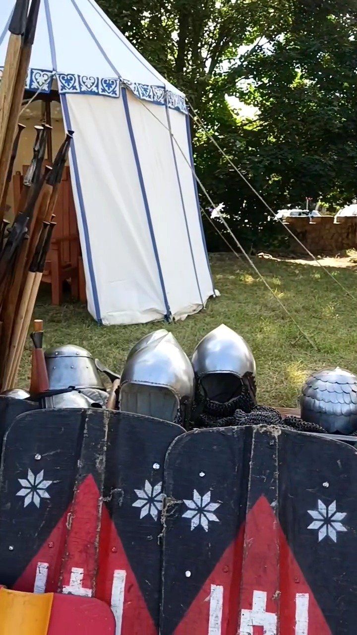 Medieval helmets and painted shields with the Atira Ruthenia star emblem in front of a white tent at the Bilohorodka history festival, September 2025